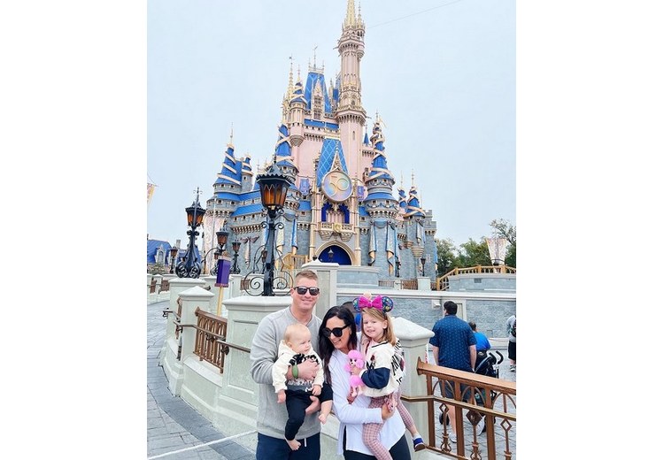 Một gia đình Việt Nam có trẻ nhỏ chụp ảnh trước cổng Disneyland California, phía sau là lâu đài cổ tích